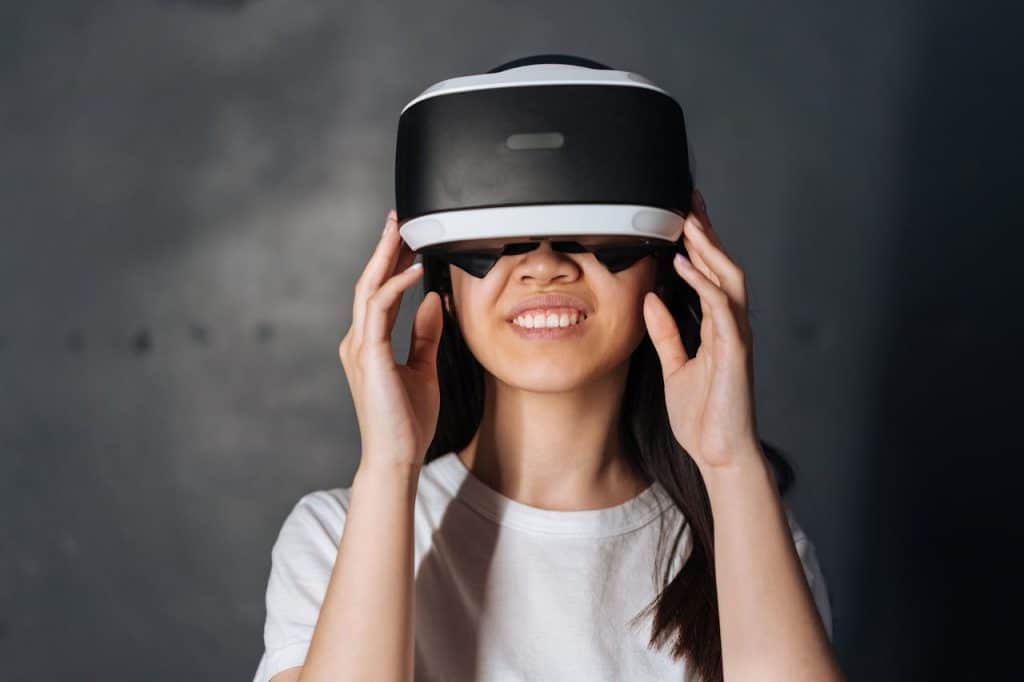 Smiling young woman immersed in virtual reality, wearing VR headset indoors.